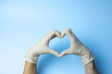 A person wearing gloves is holding their hands together to make a heart shape. Concept of care and...