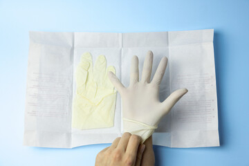 A person is holding a pair of gloves and a piece of paper with the word 