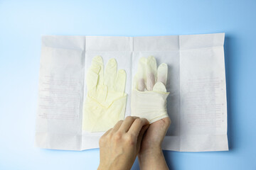 A person is wearing gloves and touching a piece of paper. The gloves are being used to protect the...