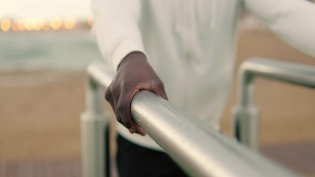 Close-up of male hands doing dips on parallel bars