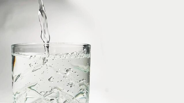 slow motion shot of pouring water into glass, closeup of bubbles in water, drinking water 