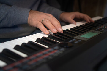Fototapeta premium Close-up of male hands playing an electronic piano. Musical education at a music school. Private music lessons with a teacher.