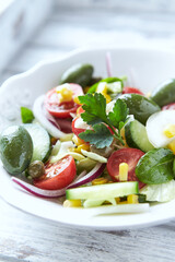 Simple Salad with Green Olives, Cucumber and Cherry Tomatoes. Bright wooden background.	