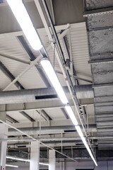 Obraz premium Ceiling mounted neon light strips inside factory roof. Low angle shot, no people