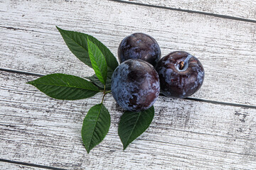 Raw purple plums heap with leaves