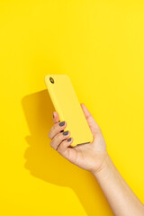 Hand holding phone on yellow background