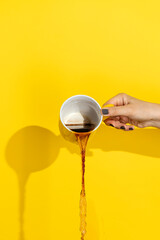 Hand pouring coffee from ceramic mug