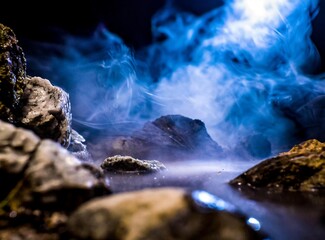 Naklejka premium Dark ambient with smoke blue tones and rocks dark illumination