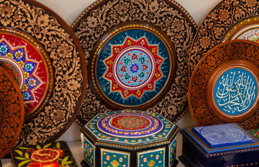 handmade Uzbek wooden plates with wood carvings hand-painted traditional patterns in the souvenir shop of Uzbekistan