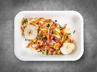 Chicken breast salad with citrus dressing. Healthy diet. Takeaway food. Eco packaging. Top view, on a gray background.