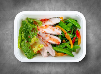 Turkey filet with fresh vegetables. Healthy diet. Takeaway food. Eco packaging. Top view, on a gray background.