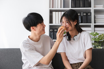Young couple sitting together on the sofa in the living room Have coffee and snacks together.