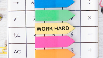 Work Hard it is written on a sticker in the shape of an arrow lying on the calculator