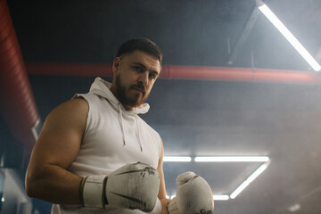 Male boxer on the background of the ring in the boxing club.