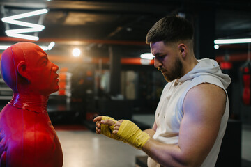 A man wraps his hands with yellow sports bandages before training. A professional athlete in a...