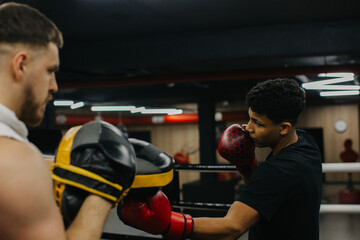 A young boxer practices punches with a trainer in a boxing studio.