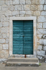closed old door in mediterranean style, greek or italian, island style, in the stone wall of the house, green-blue