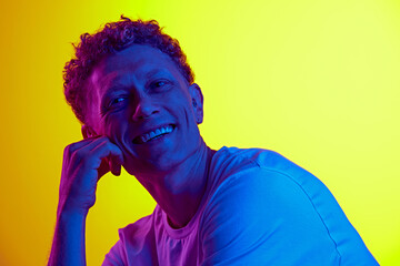 Happy smiling man with curly hair, in casual clothes expressing happiness against yellow background...