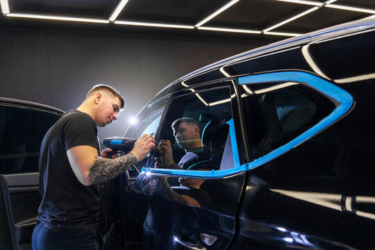 Sticker of a protective film on the headlight of a car in a car detailing studio