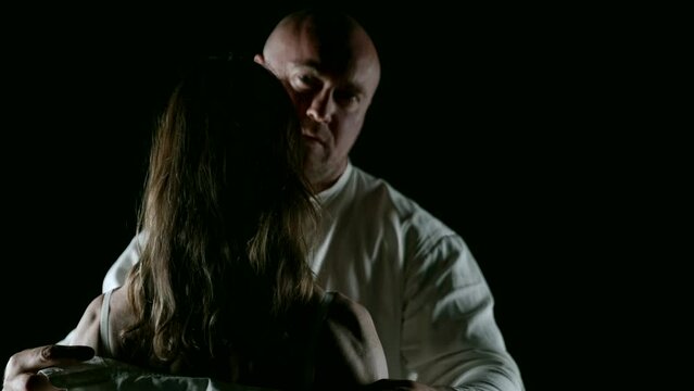 Tenderness and peace are in the air around an adult couple, framed by the contrast of a black background and white shirts, expressing their mutual affection.