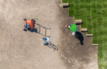 Landscaping Worker Installing Fresh Grass Turfs Aerial View.