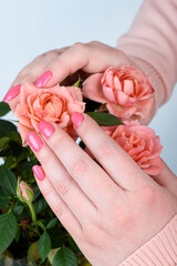 The woman's hands are embracing delicate blooming rosebuds.