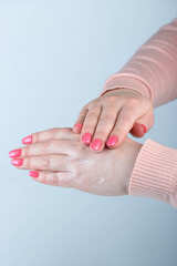A woman's hands rub moisturizer into the skin of her hands.