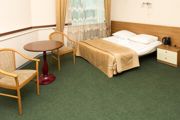 Spacious hotel room with furniture and green carpet on the floor.