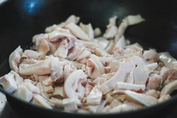Pork belly is being fried in a pan.