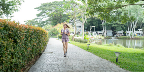 Asian fitness female sportswoman runner doing morning jogging exercise training outdoor. Happy smile woman asian running in the park