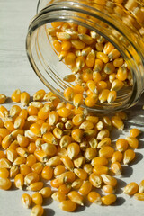 Photograph of raw pop corn in a glass jar on a table.