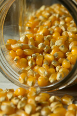 Photograph of raw pop corn in a glass jar on a table.