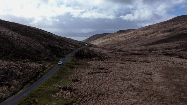 Drone footage of white car driving through mountain pass in Dingle, Ireland 4k Mavic 3 Pro