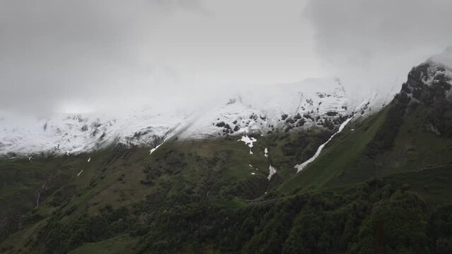Gudauri, Georgia in cloudy weather with green grass and snow on montains pics in May. 
