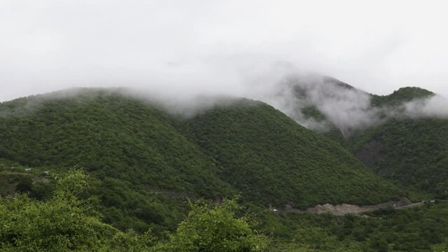 Gudauri, Georgia mountains in cloudy weather with green grass and snow on  pics in May. 