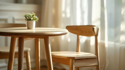 A wooden table and chair with a small plant in a sunlit room.