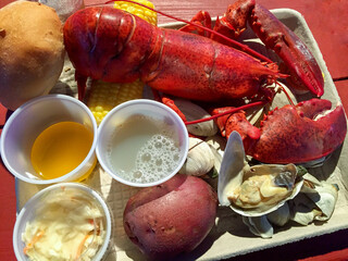 Lobster meal with clams, corn, drawn butter, coleslaw, and biscuit