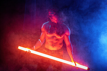 Sporty muscular man with neon light tube,colorful illumination,laser, smoke room