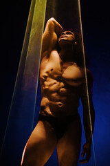 Muscular strong guy with naked torso abs under colorful illumination,laser light