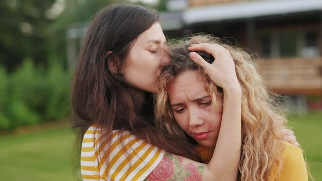 Woman becalm or console a victim of domestic violence. Woman with a scar on her face crying and hugging her friend. Concept of family problem and abusive relationship. Female suffer from her husband.