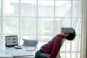 A man in a red shirt is lying down with his head on a book
