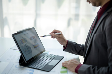 A man is sitting at a desk with a laptop and a white pen
