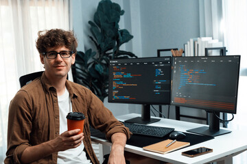 IT developer in online software development looking at camera and holding coffee cup surrounded...