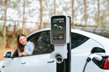 Focused EV charging station for electric vehicle's battery recharging on blurred background of...