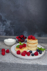 Cottage cheese pancake or syrniki with fresh raspberries and blueberry on dark wooden table.  Sweet...