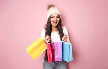 beautiful brunette young woman posing with shopping bags, isolated on pink background