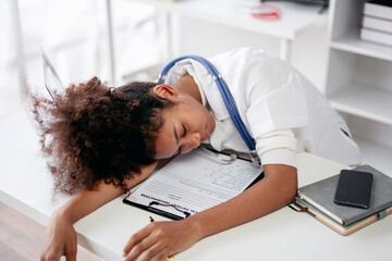 A young woman in a white lab coat is sleeping on a desk