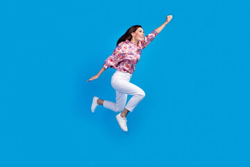 Obraz premium Full length photo of excited funky lady dressed print blouse jumping high hurrying empty space isolated blue color background