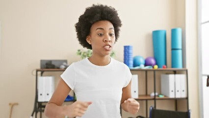 African american woman exercising indoors at a well-equipped gym, demonstrating a dynamic boxing workout pose. - Powered by Adobe