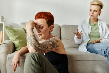 Two women, a lesbian couple with short hair, sit on a couch, engrossed in conversation